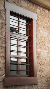 Close-up of a barred window set in a rustic stone wall, showcasing architectural details.