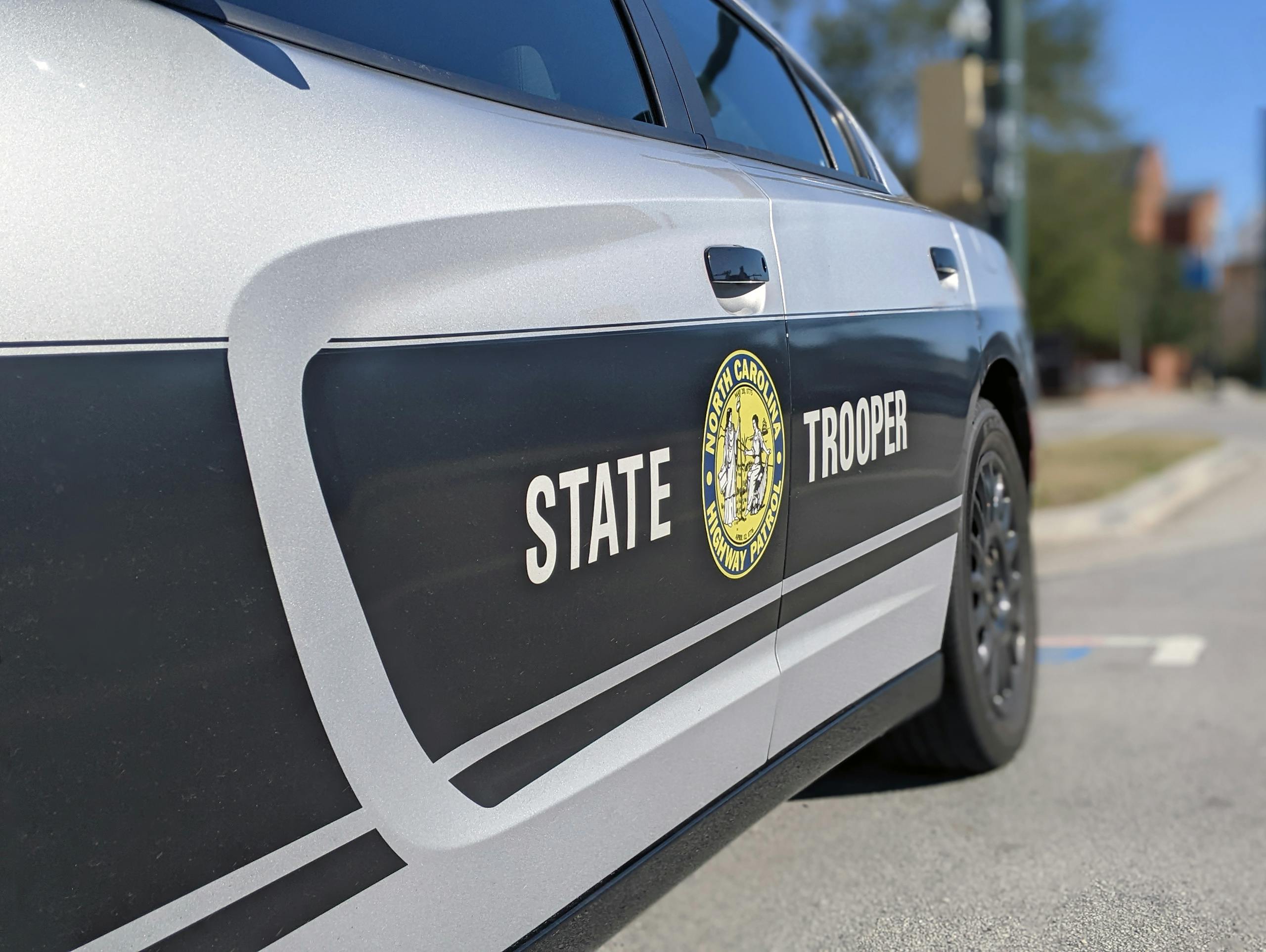 Detailed side view of a North Carolina State Trooper car in a sunny street setting.